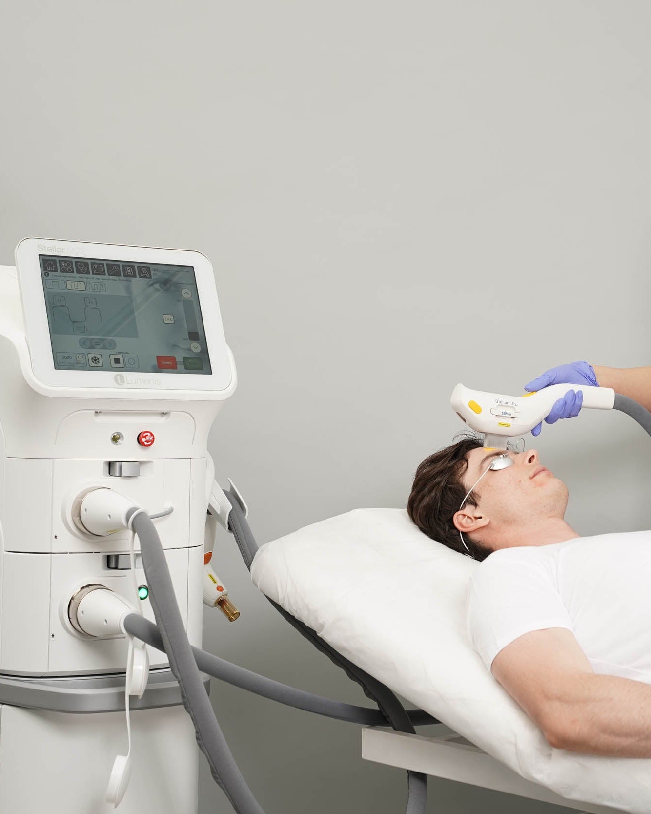 Person receiving a laser treatment from a healthcare professional in a clinical setting.