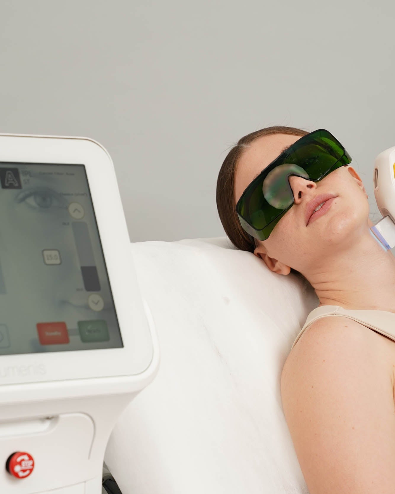 Person receiving laser treatment with protective eyewear in a clinical setting