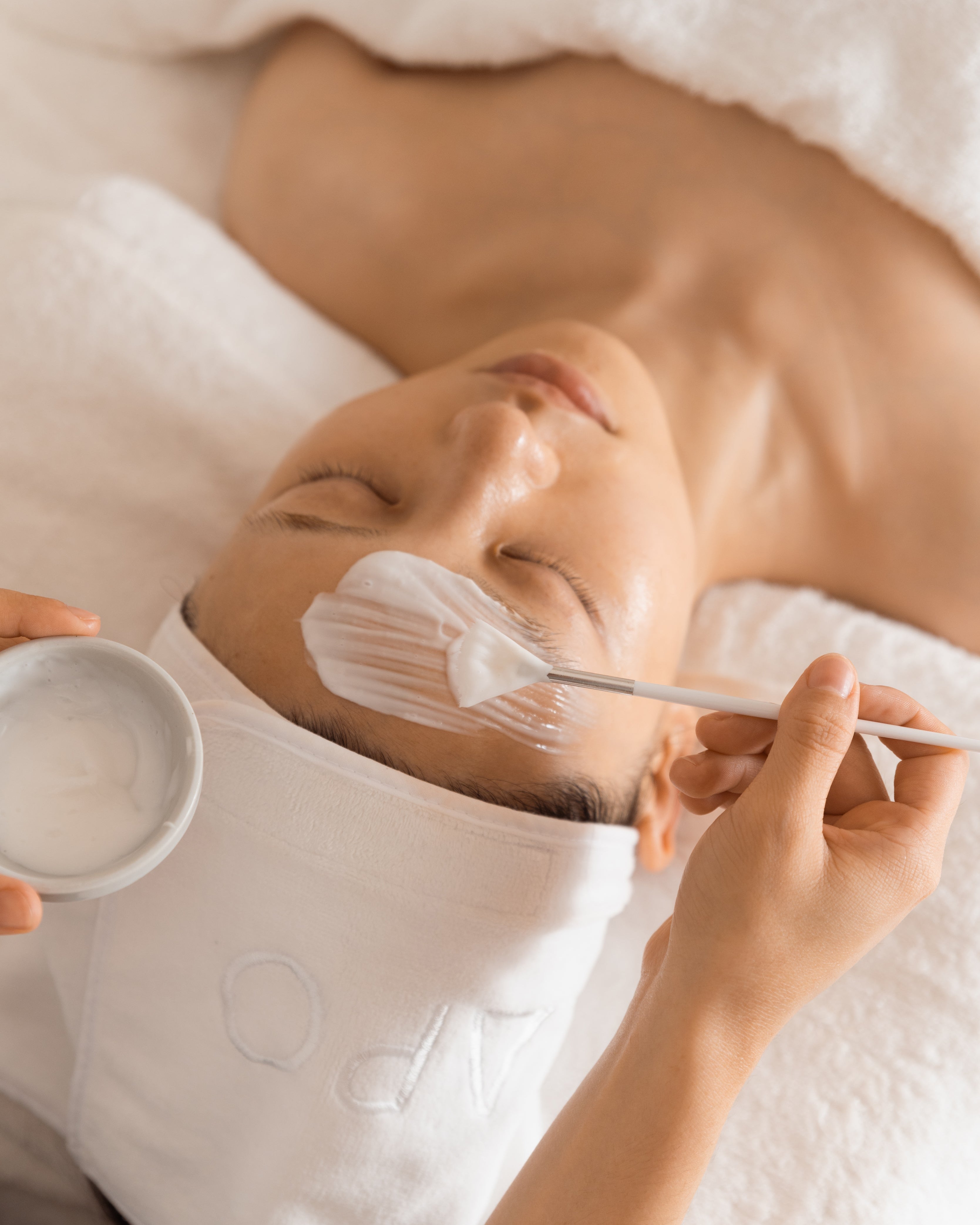 Person receiving a facial treatment with a white towel on their head